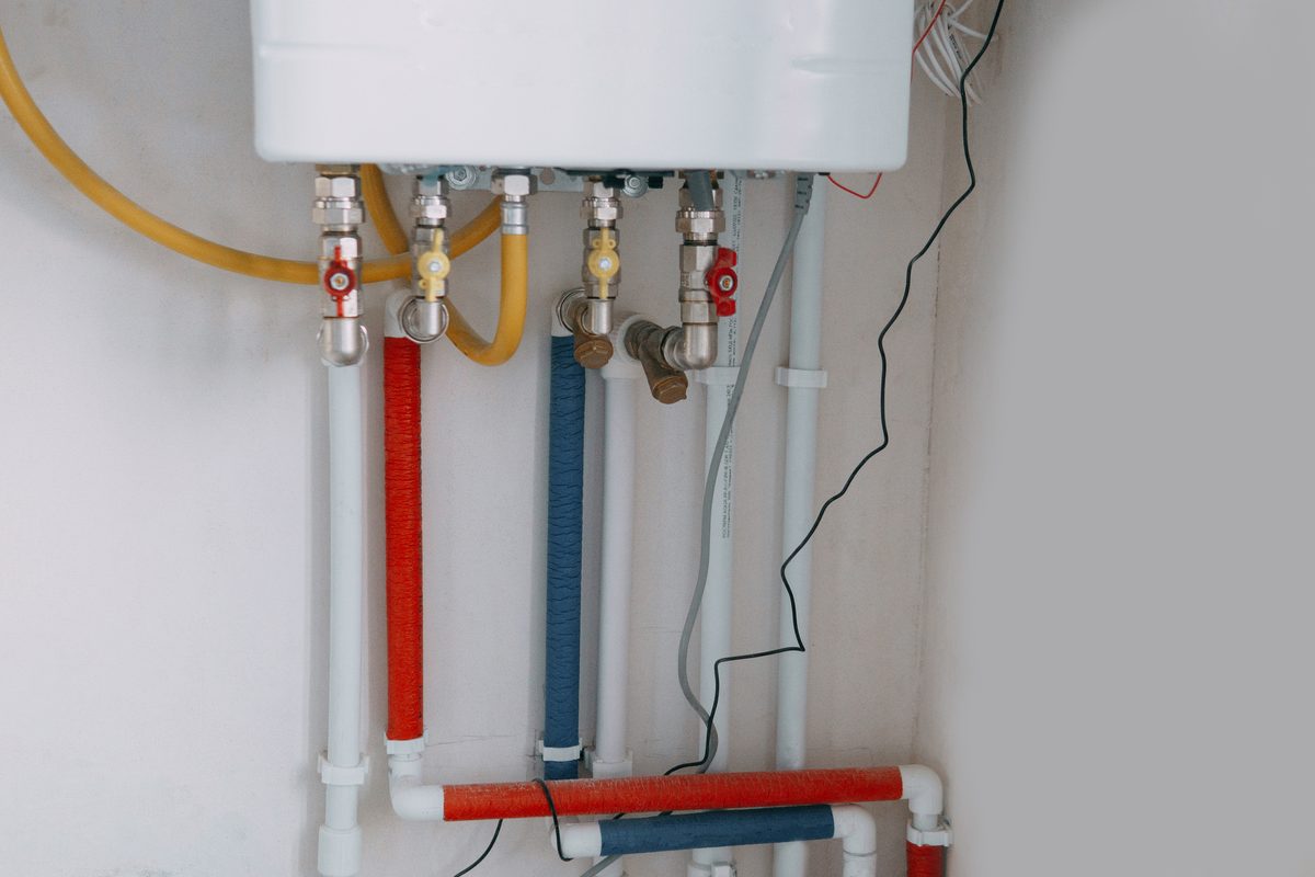 Gas boiler installation with color-coded pipes running to it
