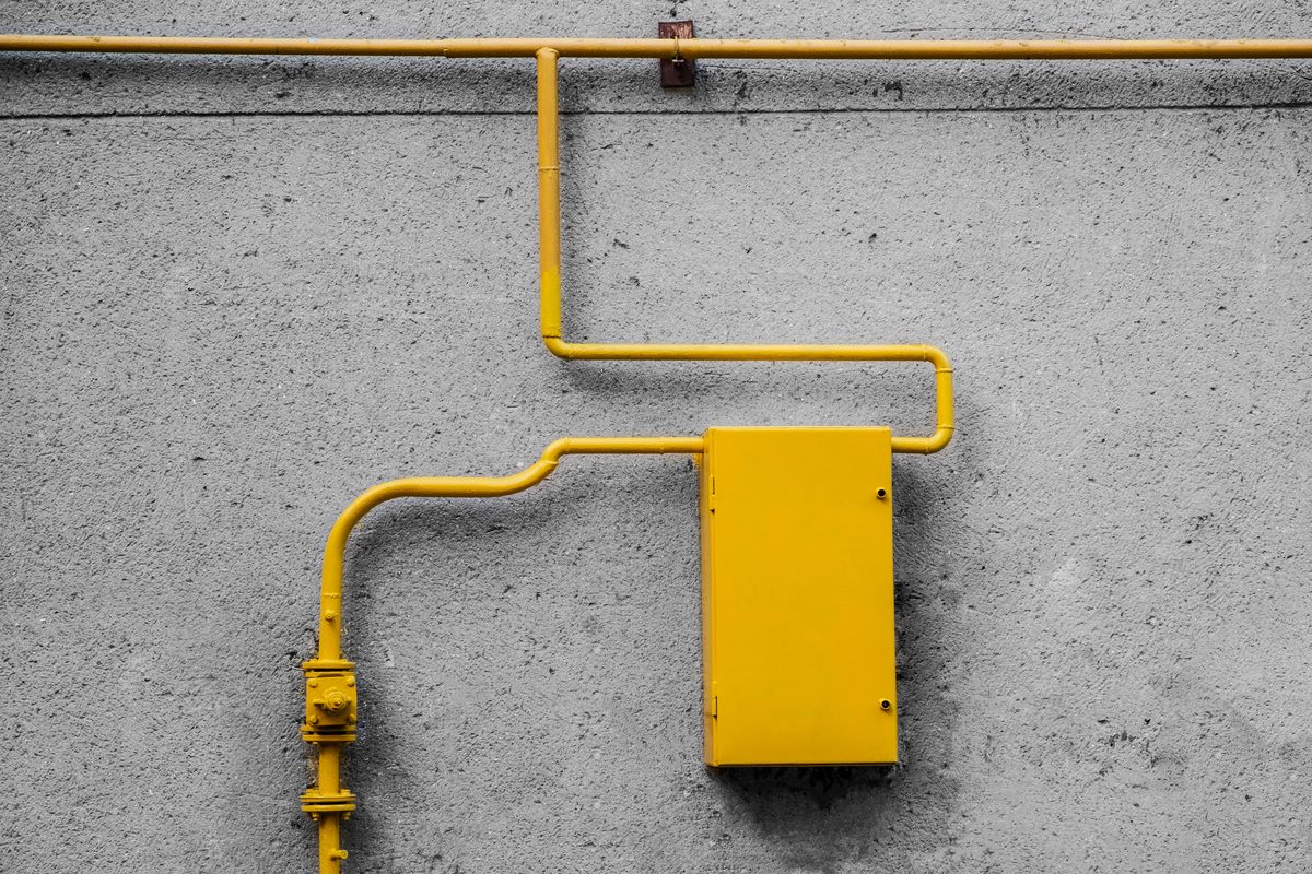 Yellow gas pipe running to a meter box on a concrete wall